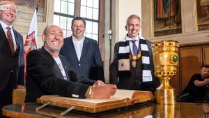 Eintracht-Präsident Peter Fischer trägt sich unter den Augen von Bürgermeister Uwe Becker, Stadtverordnetenvorsteher Stephan Sieger und Oberbürgermeister Peter Feldmann ins Goldene Buch der Stadt ein.