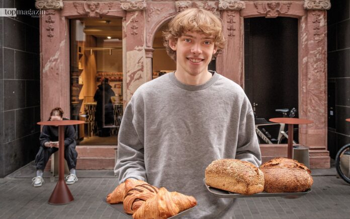 Hoppenworth & Ploch-Mitarbeiter Jan Könnecke zeigt die leckeren Brote und Croissants vor der Altstadtbäckerei in der neuen Altstadt