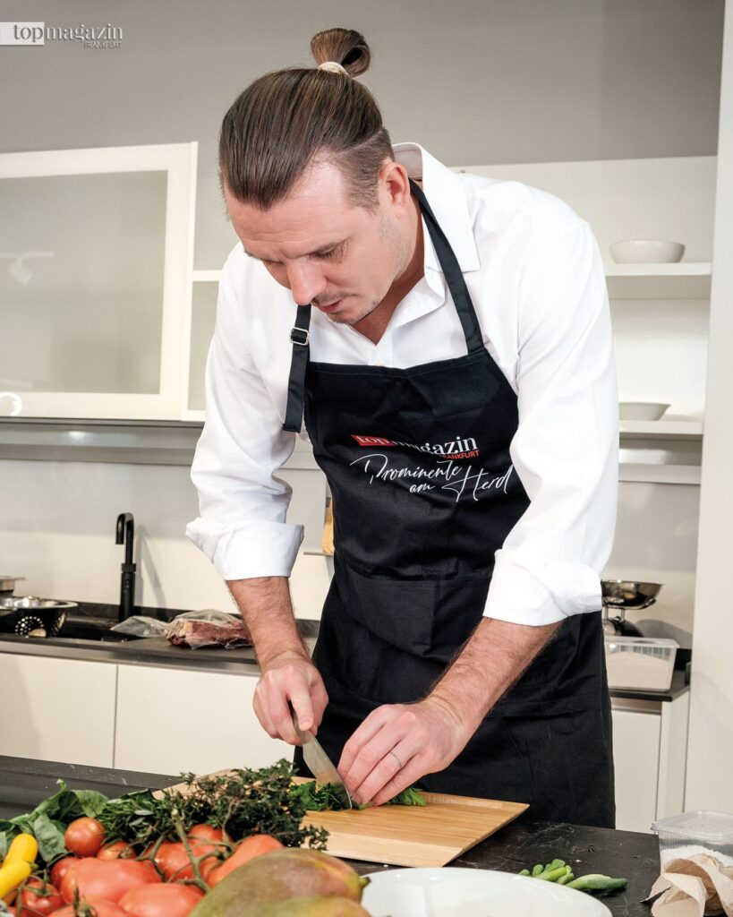 Schnippeln statt Dribbeln: Alex Meier konzentriert am Schneidemesser