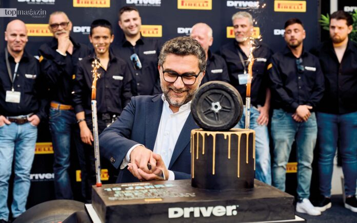 Geschäftsführer von Driver Reifen Giuseppe Pittella schneidet stellvertretend für das Team vom Driver Center Frankfurt im Hintergrund die Geburtstagstorte an