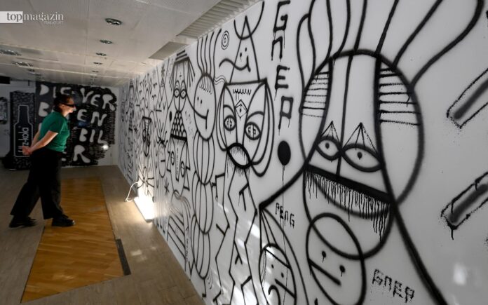 Eine Besucherin in einer Frankfurter Galerie betrachtet die großflächige, schwarz-weiße Graffiti-Wand des Künstlers Peng während der Frankfurt Art Experience 2025.