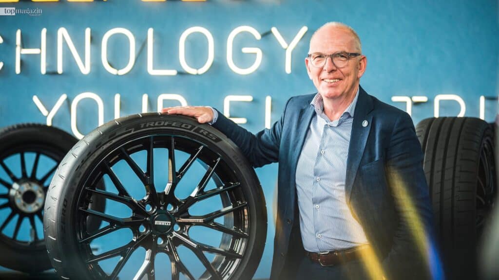 Wolfgang Meier, CEO von Pirelli Deutschland, präsentiert einen neuen Pirelli Reifen und lehnt sich dabei an eine blaue Wand mit dem Schriftzug "Technology".