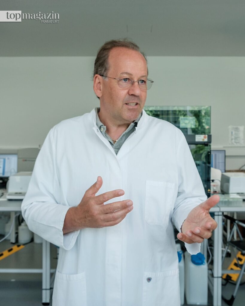 Der Wissenschaftler Dr. Johannes Coy im Laborkittel erklärt die Funktion des von ihm entdeckten TKTL1-Enzyms für die alternative Krebsforschung.