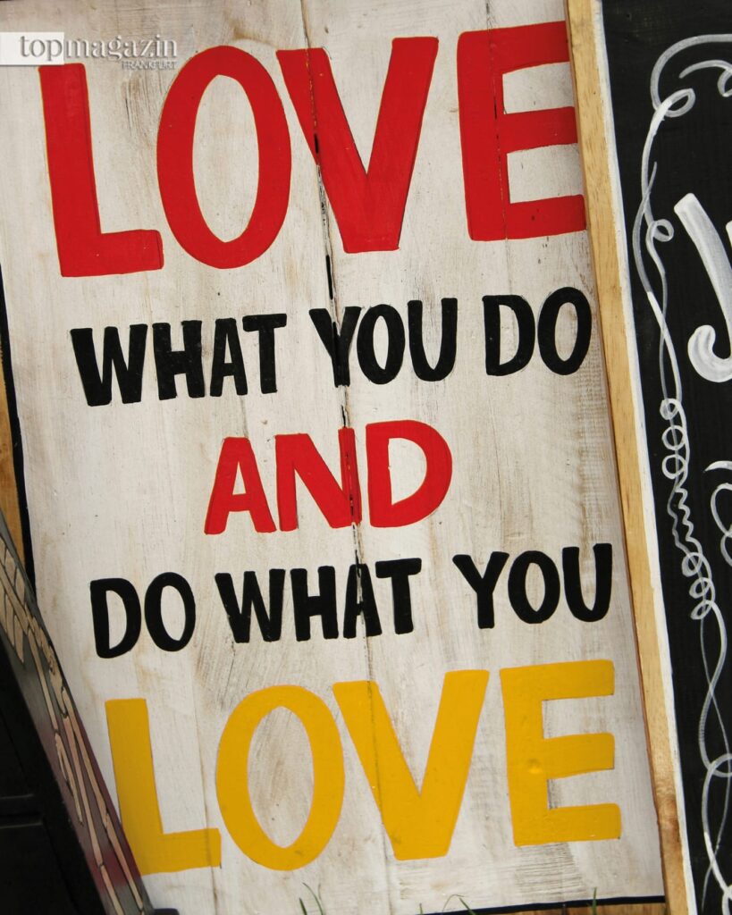Ein Holzschild mit dem Spruch "Love what you do and do what you love" als Symbol für eine erfüllende Life Balance, bei der Arbeit zur Berufung wird.