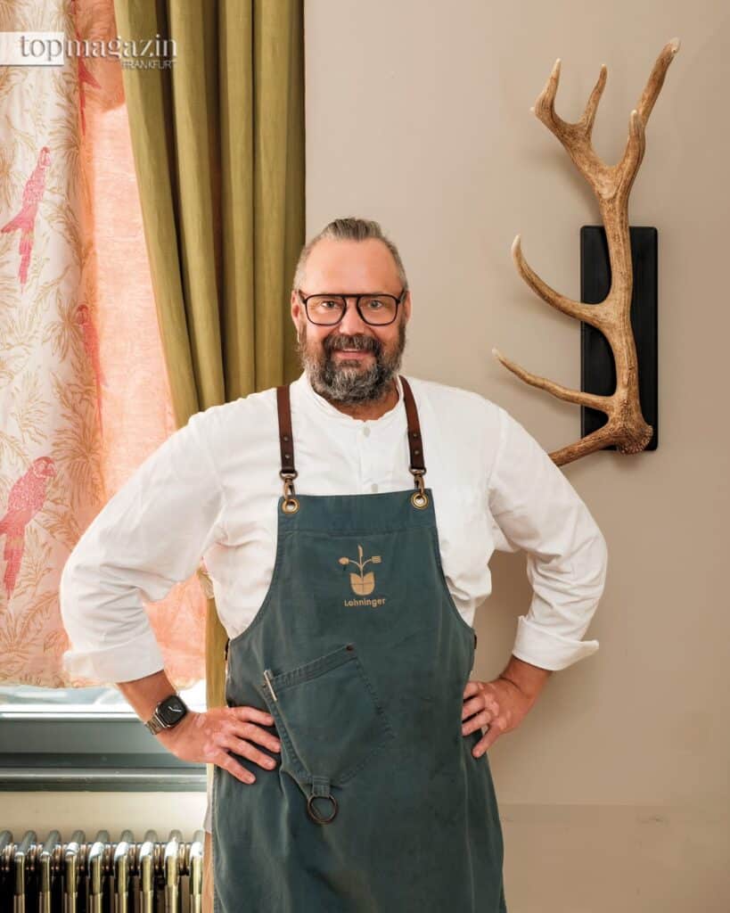 Spitzenkoch Mario Lohninger, Meister des Geschmacks, steht selbstbewusst in seinem Restaurant in Frankfurt, bekannt für das beste Wiener Schnitzel der Stadt.