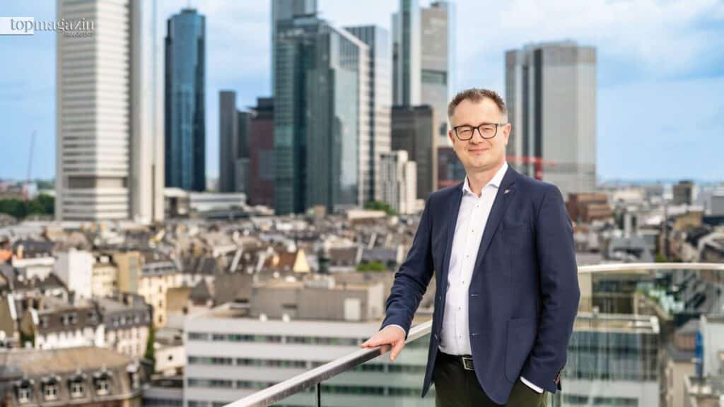 Ralf Hengels, Personalvorstand von Nestlé Deutschland, steht auf einer Terrasse mit der Frankfurter Skyline im Hintergrund.