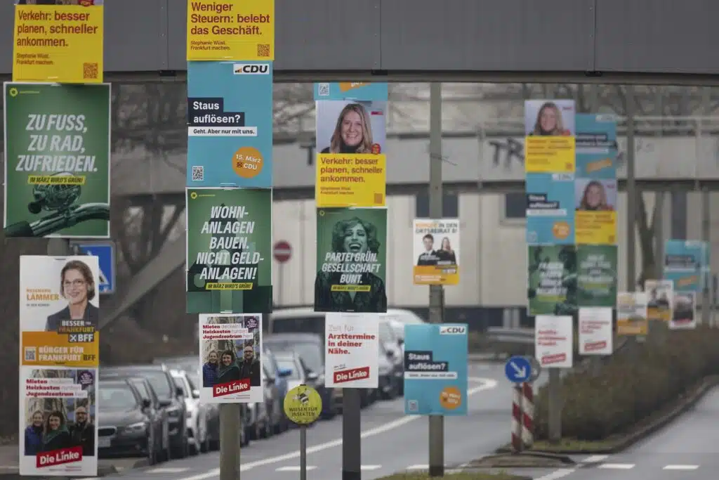 Zahlreiche Wahlplakate zur Kommunalwahl 2026 säumen eine Straße in Frankfurt am Main.
