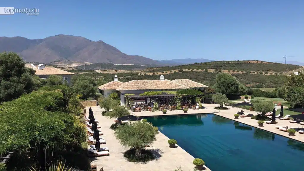 Großer, von Palmen gesäumter Salzwasser-Pool der Finca Cortesin vor der bergigen andalusischen Landschaft.