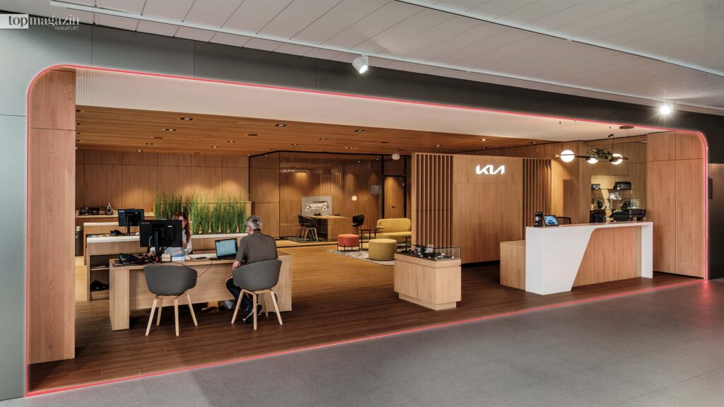 Stilvoller Lounge-Bereich im Kia Autohaus mit warmen Holztönen, klarem Design und modernen Beratungscountern.