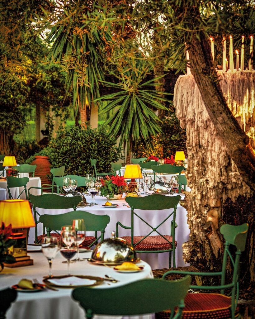 Elegant gedeckte Tische im romantischen Garten des Grill-Restaurants im Marbella Club unter üppigen Bäumen und sanftem Licht.