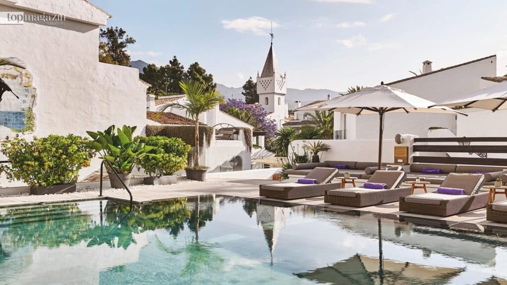 Ein ruhiger, glasklarer Pool, umgeben von eleganten Sonnenliegen und weißen andalusischen Gebäuden im Nobu Hotel Marbella.