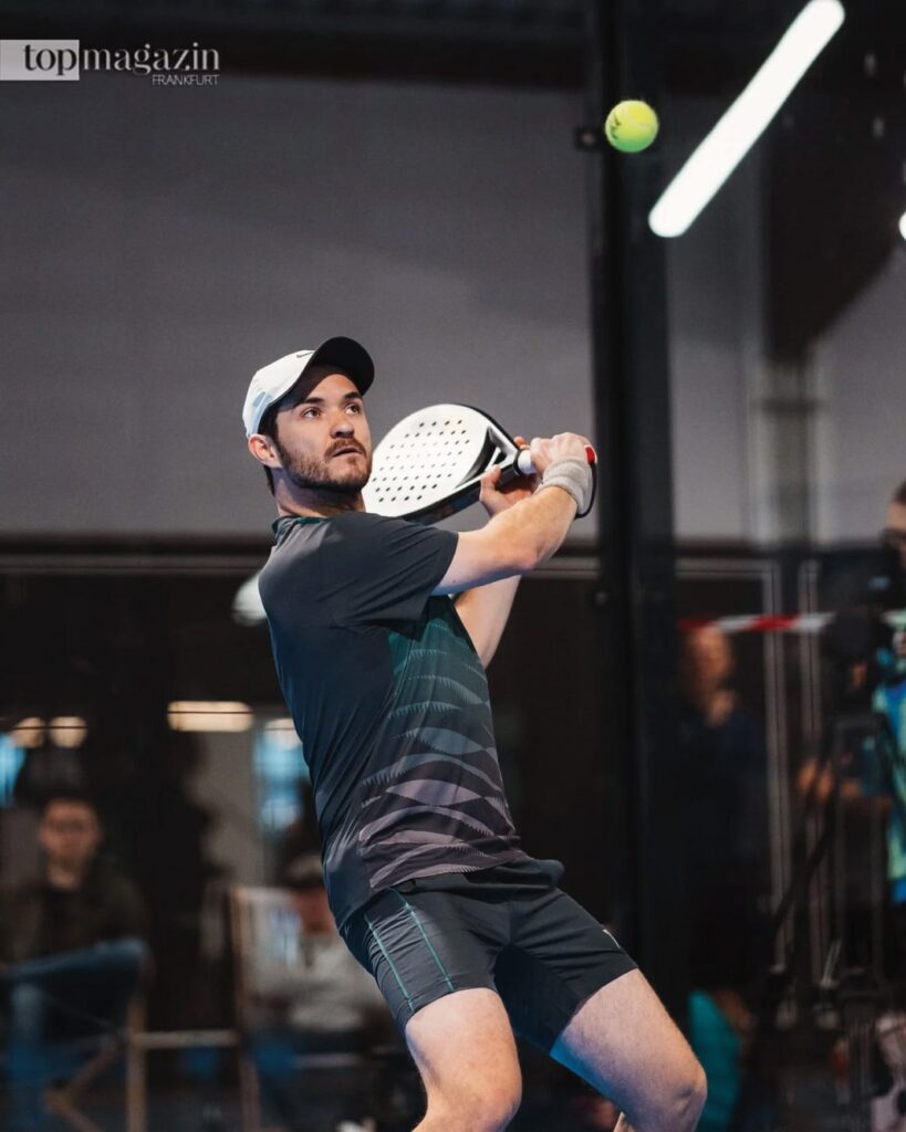 Patrick Mayer vom Hessischen Tennis-Verband schlägt einen Padel-Ball in einer modernen Indoor-Halle.
