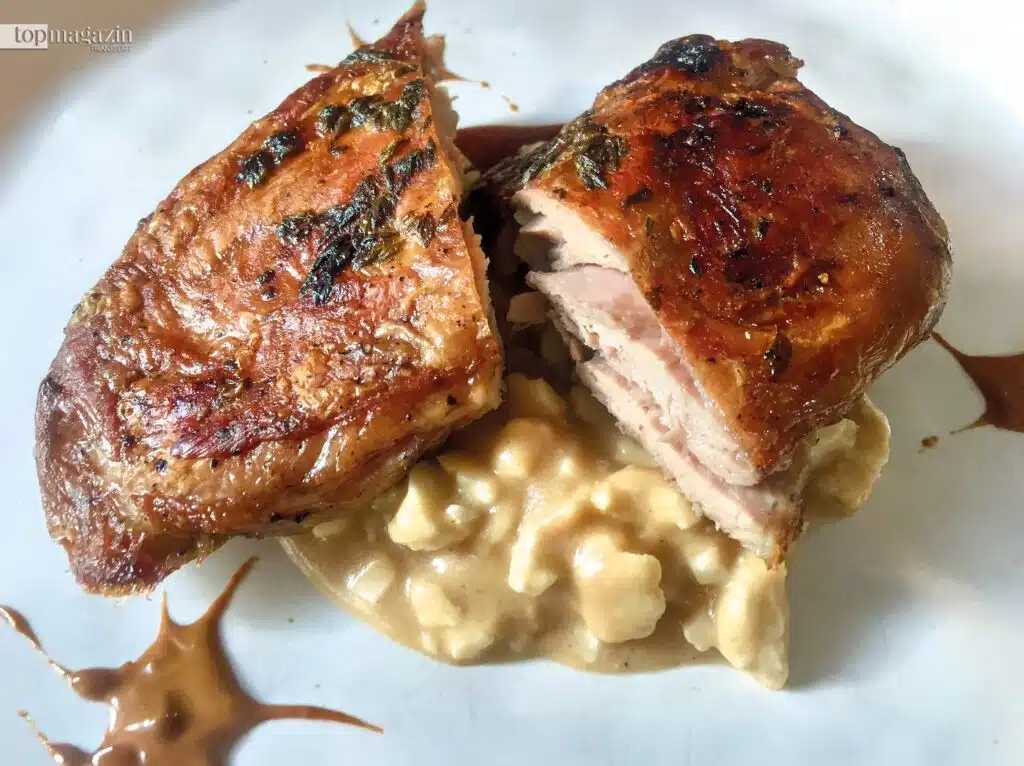 Aufgeschnittenes, saftiges Fleisch vom schwarzen Kastanien-Schwein mit einer feinen Kruste auf einem weißen Teller.