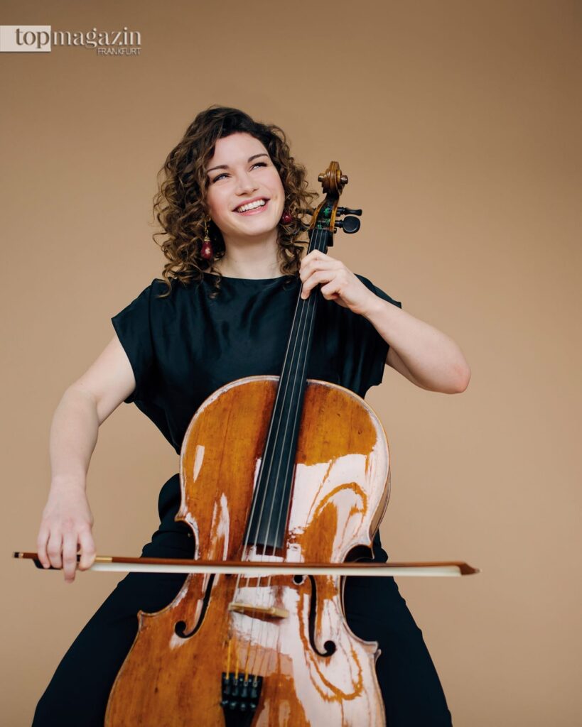 Die lächelnde Cellistin Julia Hagen spielt schwungvoll auf ihrem Cello.