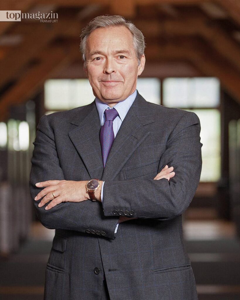 Porträt von Karl-Friedrich Scheufele, Co-Präsident von Chopard, im Anzug vor einem verschwommenen Raum.