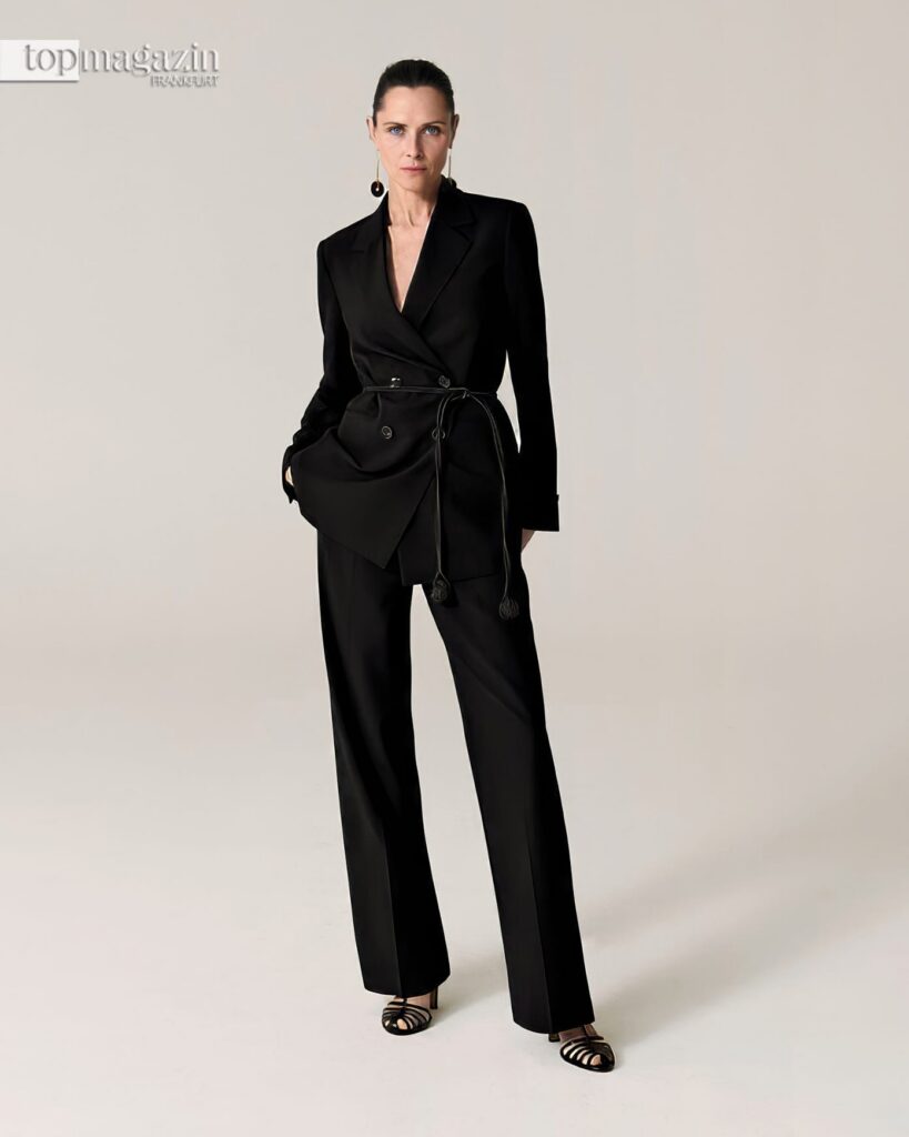 Eine Frau im eleganten, schwarzen Zweireiher-Hosenanzug von Comma als Beispiel für minimalistischen Stil und Capsule Wardrobe.