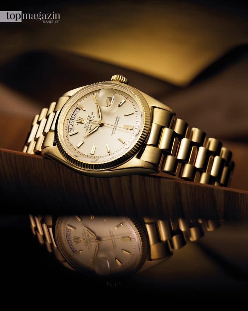 Eine goldene Rolex Day-Date Automatikuhr auf edlem Holz liegend mit Spiegelung.