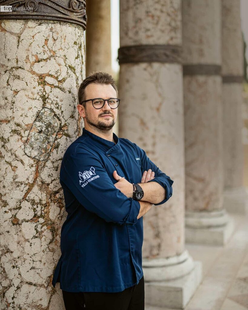 Porträt von Küchenchef Mattia Bartoli in blauer Kochuniform an einer steinernen Säule in der Villa Cortine Palace.