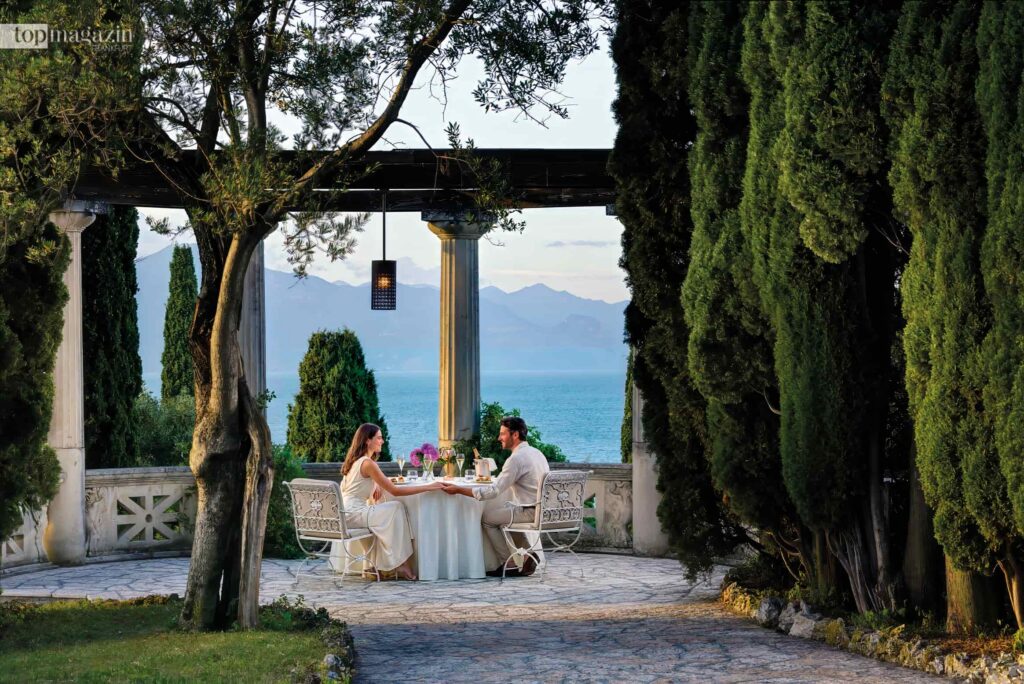 Paar genießt ein romantisches Dinner auf der Terrasse der Villa Cortine Palace am Gardasee.