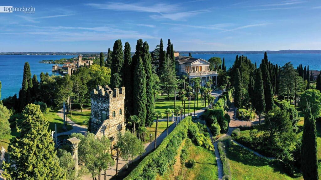 Weitläufiger Park der Villa Cortine Palace in Sirmione mit Zypressen und Seeblick.