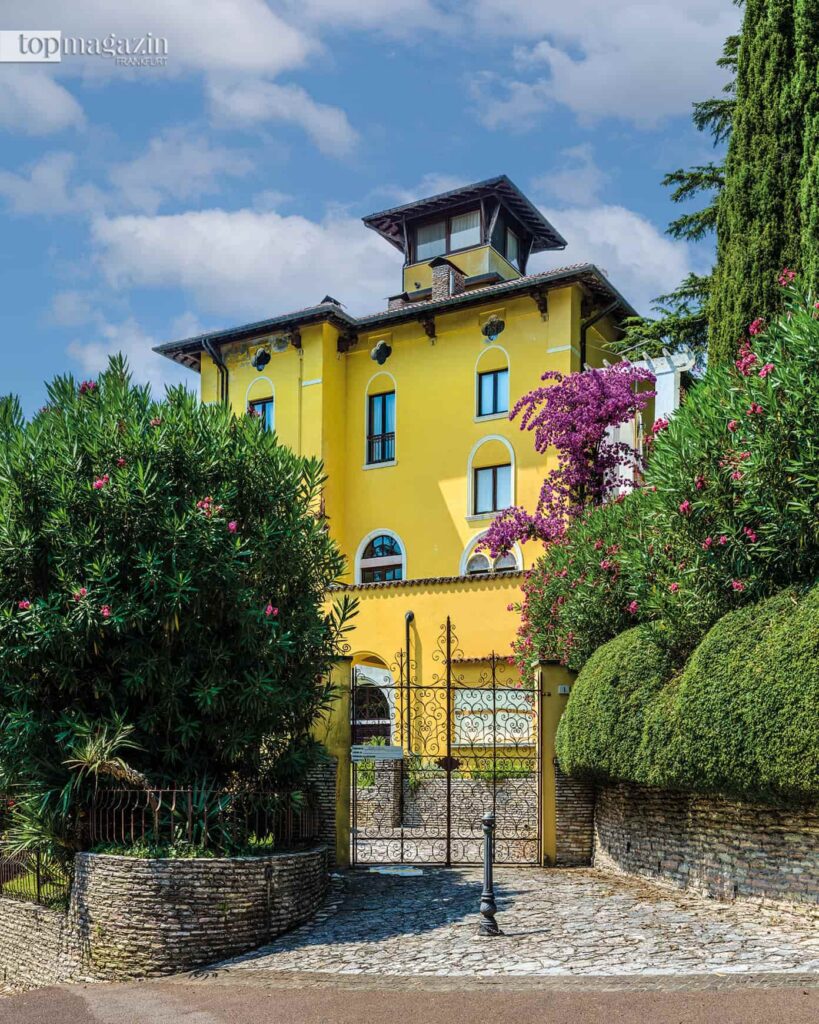 Die leuchtend gelbe Villa Meneghini-Callas mit schmiedeeisernem Tor in Sirmione am Gardasee.