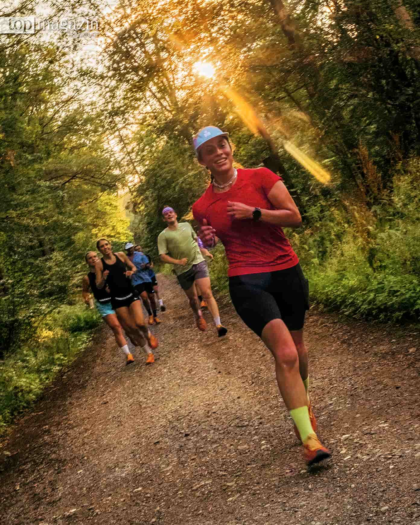Läuferin mit Kappe führt eine Gruppe des Irregular Practice Run Club über einen Waldweg bei Frankfurt