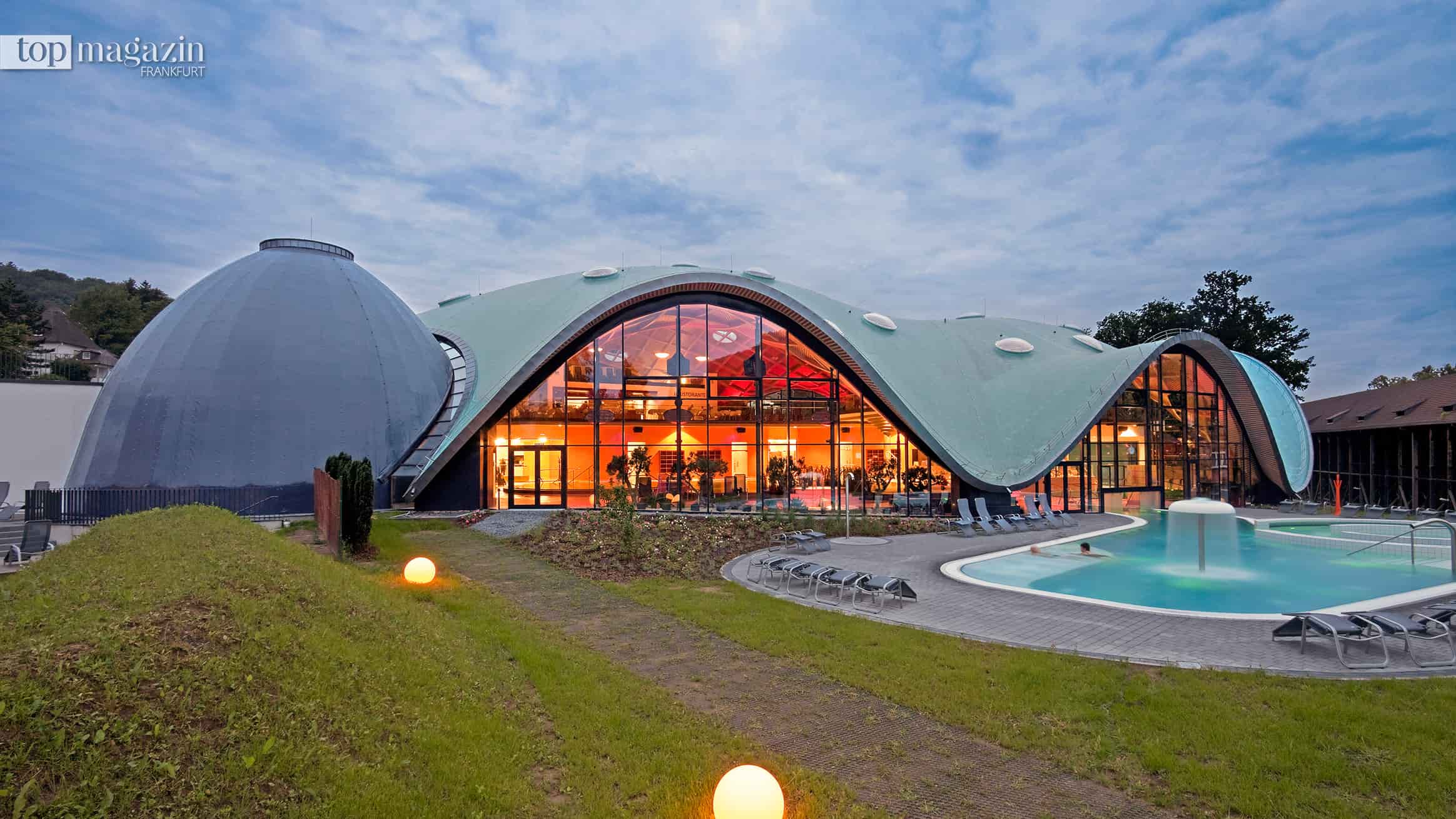 Kuppelbau der Toskana Therme in Bad Orb in der Abenddämmerung, davor das beleuchtete Außenbecken